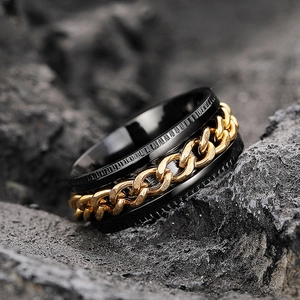 Macro shot of men's black industrial ring with gold curb chain inlay on volcanic stone