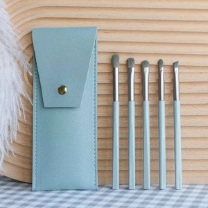 Detailed view of five professional light blue makeup brushes with a matching leather case