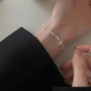 Handmade woven S925 sterling silver geometric bracelet worn on wrist with black sleeve