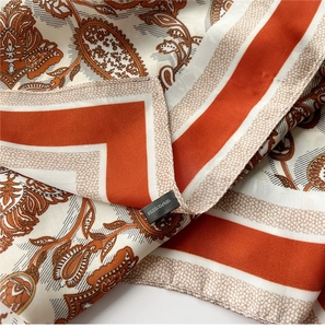 Detailed macro view of soft orange and cream polyester scarf with fine rolled edges