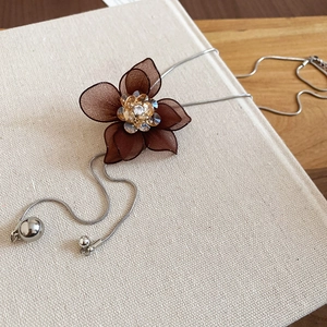 Detail of mesh flower necklace with crystal core on silver chain and metallic beads