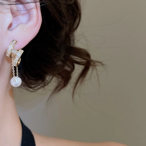 Close-up of gold geometric earrings with rectangle zircons and white round pearls