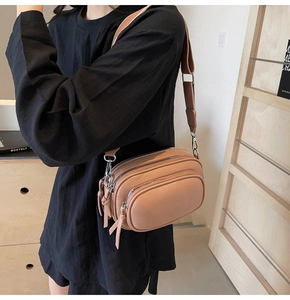 Detail of pink crossbody bag with litchi texture leather and multi-layer zippers