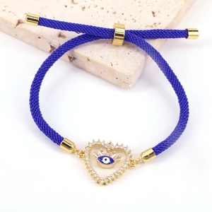 Macro shot of blue braided evil eye bracelet with heart zircon pendant on stone