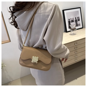 Gros plan d'un sac bandoulière marron avec boucle dorée sur cuir mat texturé