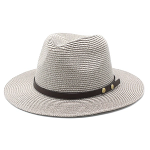 Detailed close-up of straw Fedora hat with fine texture and brown leather decorative band
