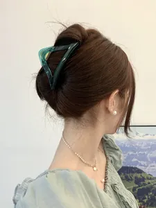 Close-up of a green triangular hair claw clip with a glossy finish on styled hair