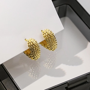 Gros plan détaillé de boucles d'oreilles dorées à texture torsadée sur carte blanche