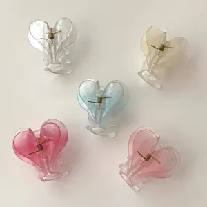 Top view of five transparent heart-shaped hair claws in pastel colors on a white background