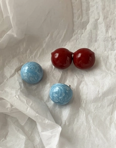 Vue détaillée des boucles d'oreilles boules rouge foncé et bleu marbré sur papier froissé