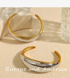 Close-up of chunky gold and silver contrast open cuff bracelets with polished texture