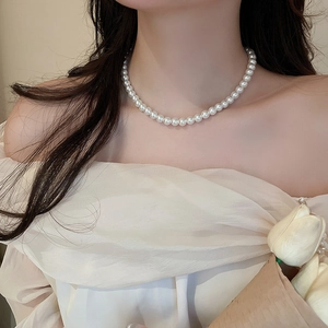 Close-up of a French style white pearl choker necklace worn on a model's collarbone