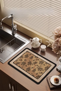 Detail of vintage floral absorbent kitchen mat on wooden countertop near the sink