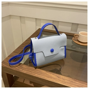 Detail of blue textured patchwork leather handbag with shoulder strap on a table