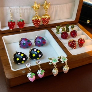 Detail of fruit themed earrings including strawberry and grape designs in a jewelry box