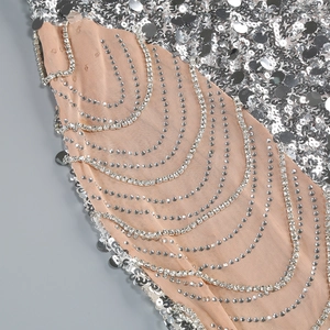 Detail of silver sequins and rhinestone chains on nude mesh fabric of the evening gown