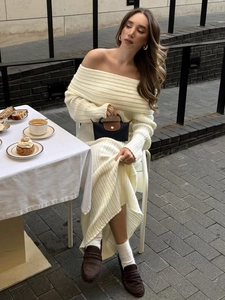 Detailed texture of off-white ribbed knit fabric on an off-shoulder long sleeve dress