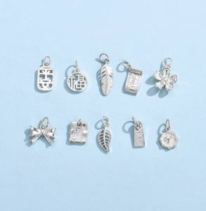 Flat lay of diverse 925 sterling silver DIY charms including feather and lucky symbols