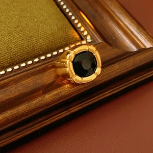 Macro di un anello vintage dorato con zircone nero quadrato su sfondo di pelle scura