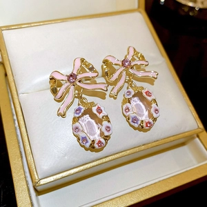 Detail of pink bow drop earrings with crystals resting in a white jewelry box