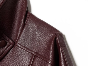 Détail du grain de litchi et des coutures sur la veste en cuir PU rouge foncé