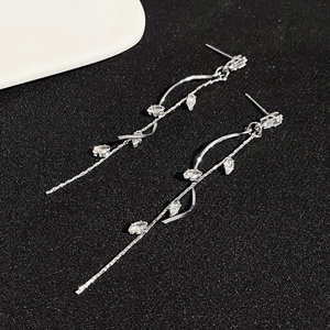 Macro shot of silver tassel earrings with vine-shaped cubic zirconia on black background