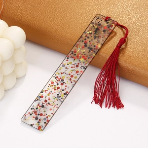 Detail of transparent acrylic rectangle bookmark with red tassels and colorful sequins