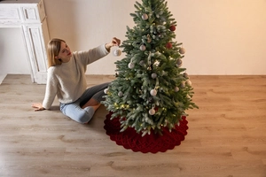 Dettaglio della gonna per albero di Natale in maglia rossa con pompon decorativi