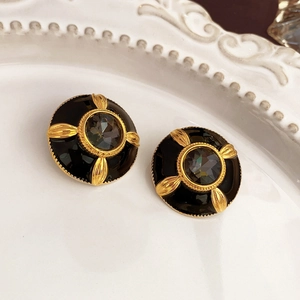 Detailed view of vintage gold and black floral stud earrings with dark grey gemstone