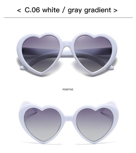 Macro detail of white heart-shaped sunglasses featuring gradient grey polarized lenses