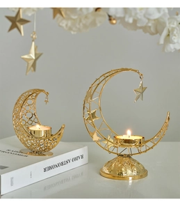 Close-up of golden crescent moon candle holders with intricate cutout patterns and star charms