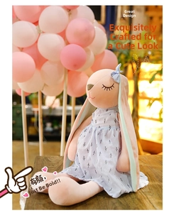Detail of pink long-eared bunny plush toy wearing a light blue floral dress and bow