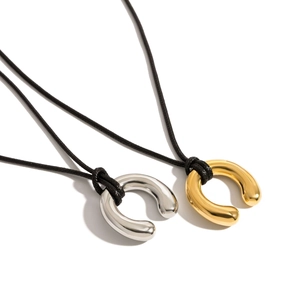 Close-up of horseshoe-shaped gold and silver metal pendants on black cord necklaces