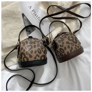 Detail of leopard print bucket bags with black and brown leather trim on white plush fabric