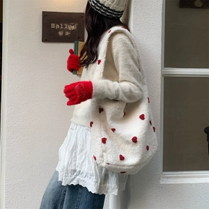 Detail of white plush tote bag with red heart embroidery and winter accessories
