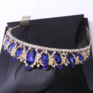 Golden bridal tiara with blue gemstones and sparkling rhinestones on a black stand