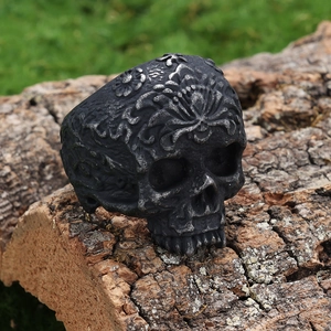 Vintage oversized skull ring with floral carvings on natural tree bark background