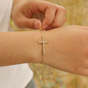 Gold box chain bracelet with sparkling zircon cross pendant on a female wrist