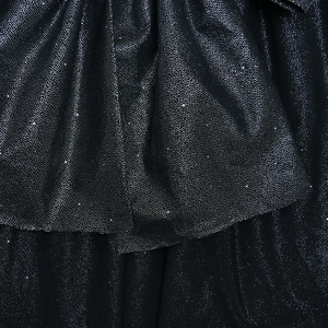 Close-up of black fabric with silver glitter finish showing elegant draped texture