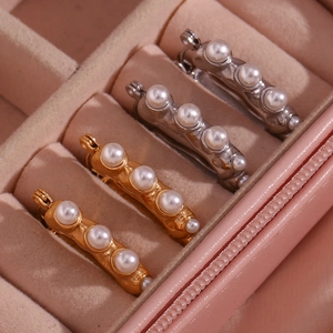 Detailed macro view of gold and silver U-shaped hoop earrings with pearls in a pink jewelry box