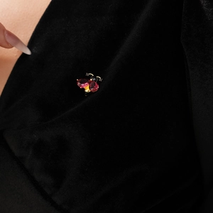 Detail of bee brooch with purple gemstone and gold enamel on black velvet fabric