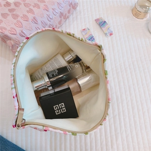 Interior view of floral fabric makeup bag with multiple cosmetic items and beige canvas lining