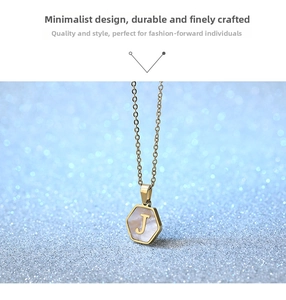 Macro detail of hexagonal golden pendant with white shell inlay and letter J engraving