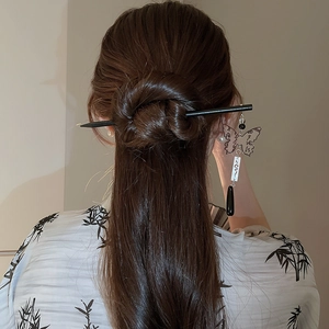 Detail of butterfly tassel hairpin with black drop pendant on elegant bun hairstyle