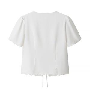 White short sleeve blouse featuring scalloped hem and tie-up detail on white background