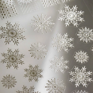 Macro detail of white 5D embossed snowflake nail stickers with delicate 3D texture and patterns