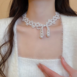 Detailed view of elegant pearl bow necklace worn on the collarbone with soft luster