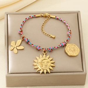 Detail of woven Bohemian bracelet featuring gold sun and flower pendants on a jewelry box