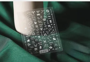 Macro view of 5D white constellation nail art stickers on dark green textured fabric