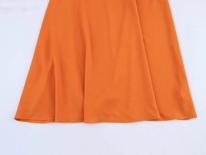 Vue macro détaillée de l'ourlet fluide de cette robe de plage orange à taille haute